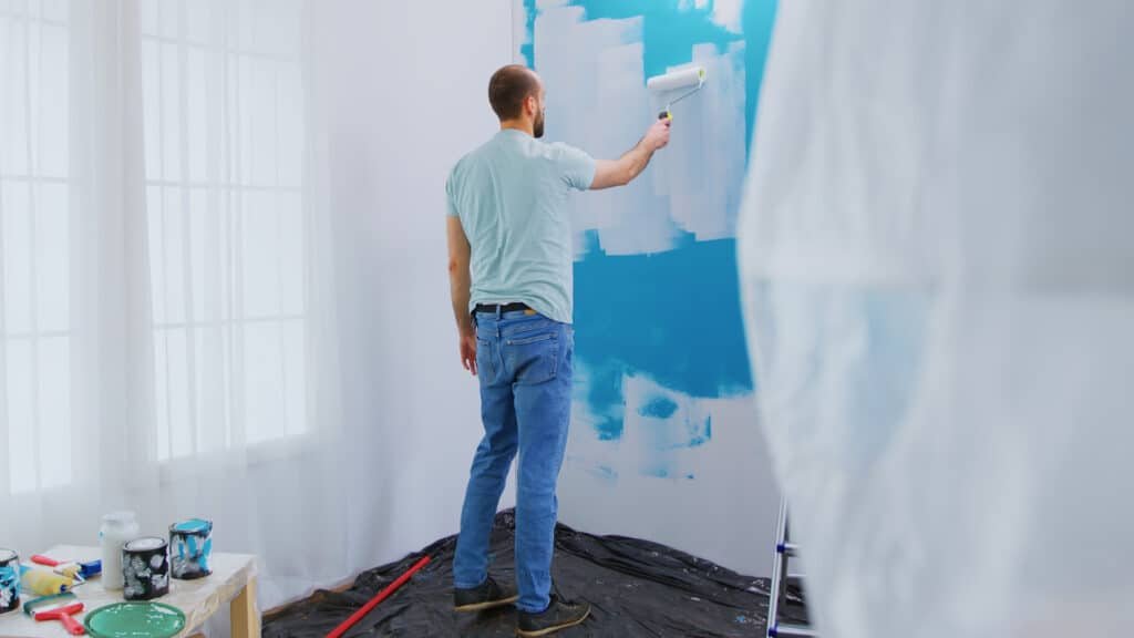 homme qui repeint un mur de couleur bleue