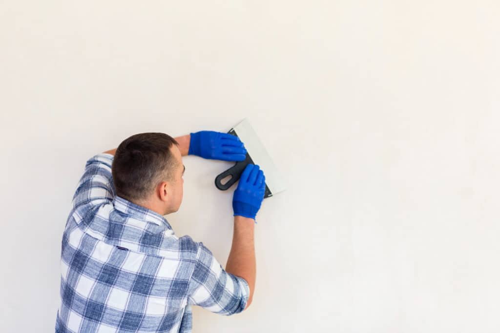 Homme qui rénove un mur avec un outil